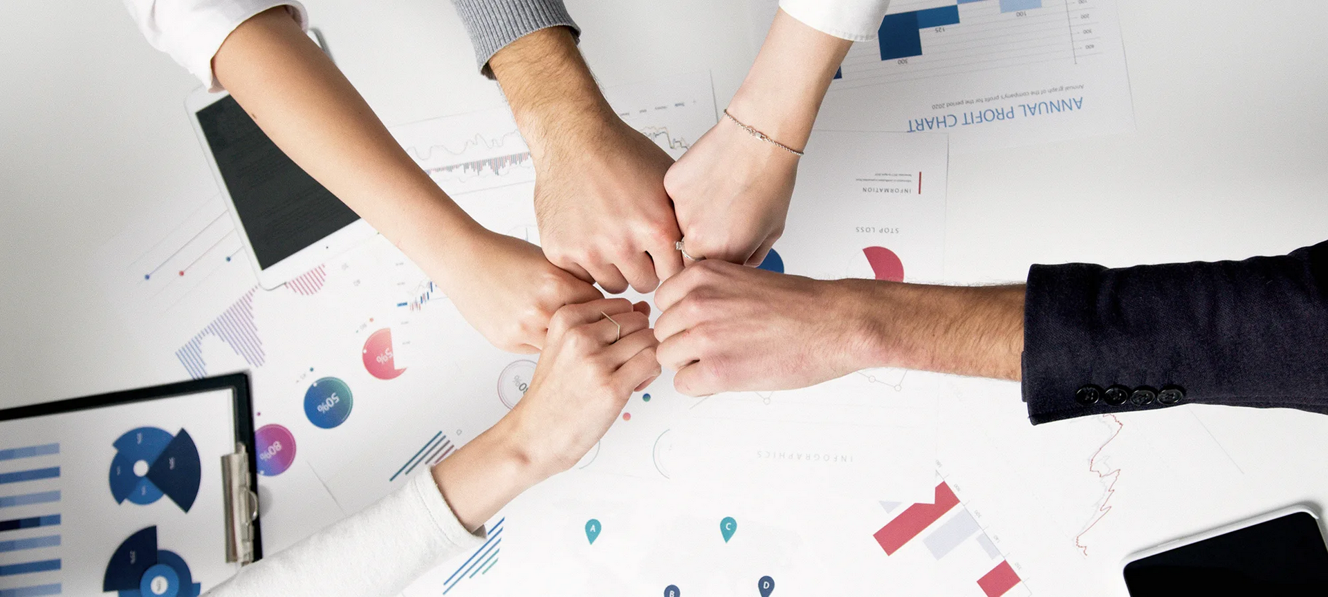 Team members joining hands over business reports